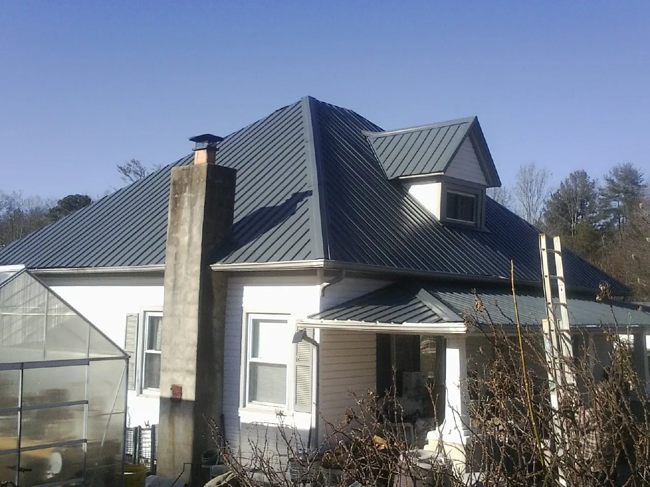 Dark blue standing seam metal roof on a white farmhouse with dormer — Slate & Tile Roof Repair by Roofing Brothers in Potrero