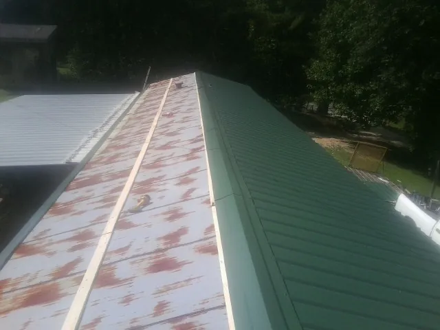 Old rusted panels beside newly installed green metal roofing — Wind Damage Roof Repair by Roofing Brothers in Potrero