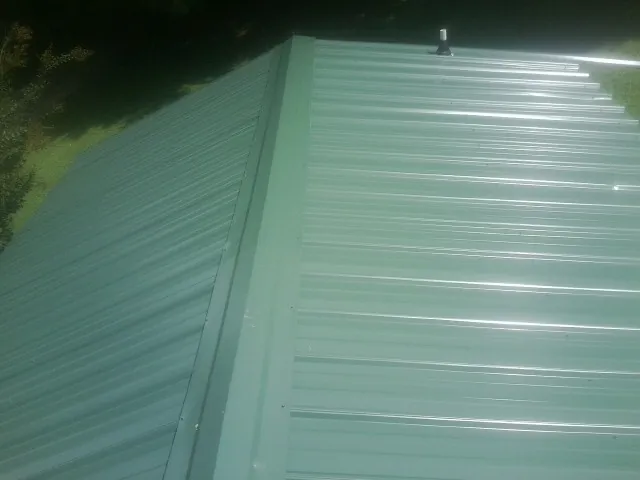 New green metal panels meeting at the ridge of a roof — Flat Roof Repair work by our crew in Potrero