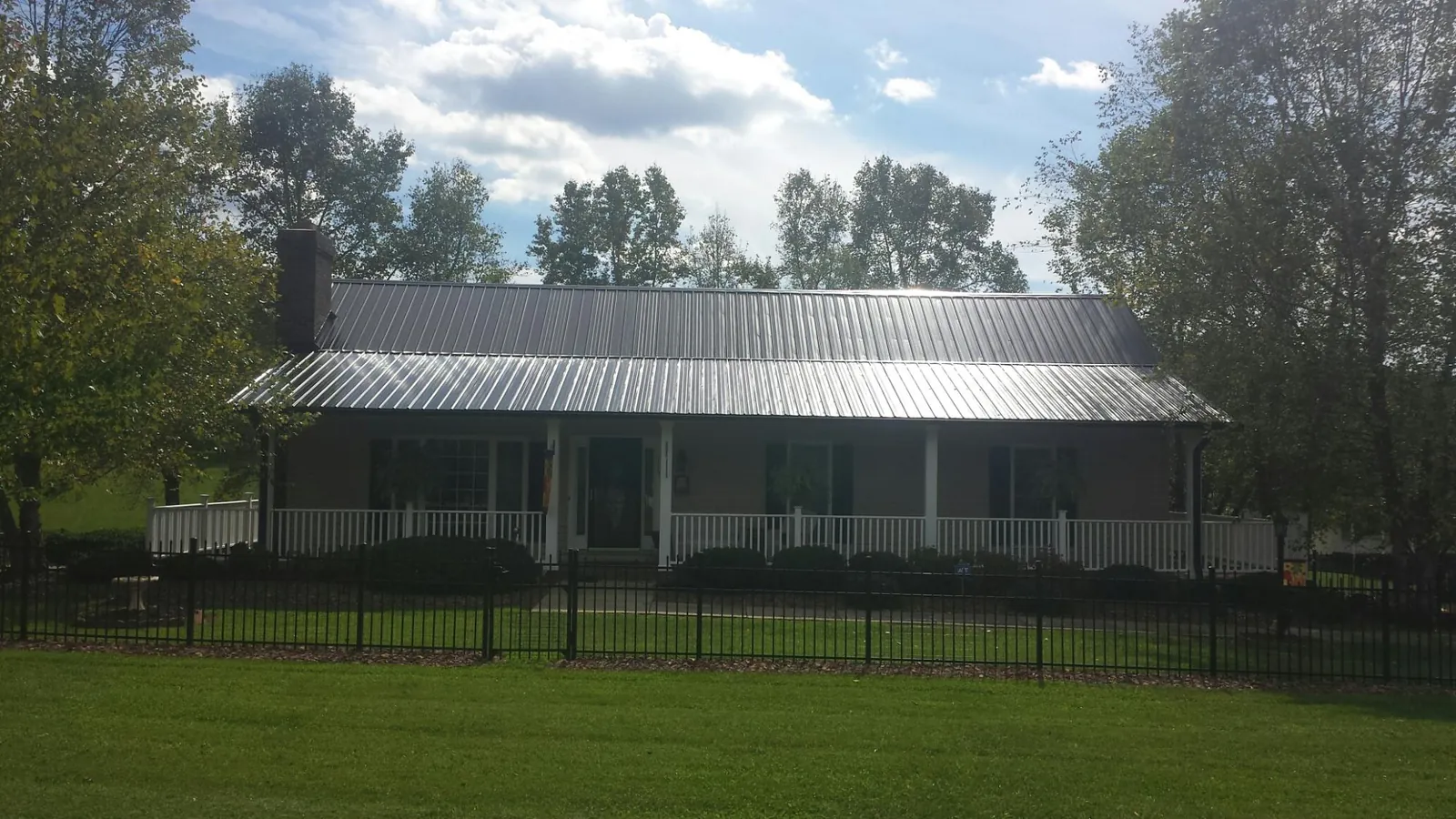 Gray metal roof on a brick ranch with a full width front porch — Gutter Guard Installation work by our crew in Potrero